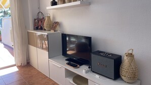 Una sala de estar moderna con un televisor de pantalla plana, un altavoz Marshall y objetos decorativos en una estantería.