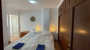 Habitación de hotel con cama, lámparas de noche, un adorno circular en la pared y un armario de madera.