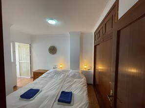A hotel room with a bed, bedside lamps, a round wall decoration, and a wooden wardrobe. - Apartment 'Nerja Burriana Beach' with Sea View, Wi-Fi and Air Conditioning (Nerja)