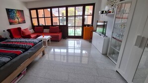 A compact living space with a bed, sofa, dining table, and a refrigerator. - Cozy vacation apartment with a beautiful terrace (Bad Windsheim)