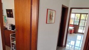 A hallway with a wooden door, a black mat, and a kitchen area in the background. - Cozy vacation apartment with a beautiful terrace (Bad Windsheim)