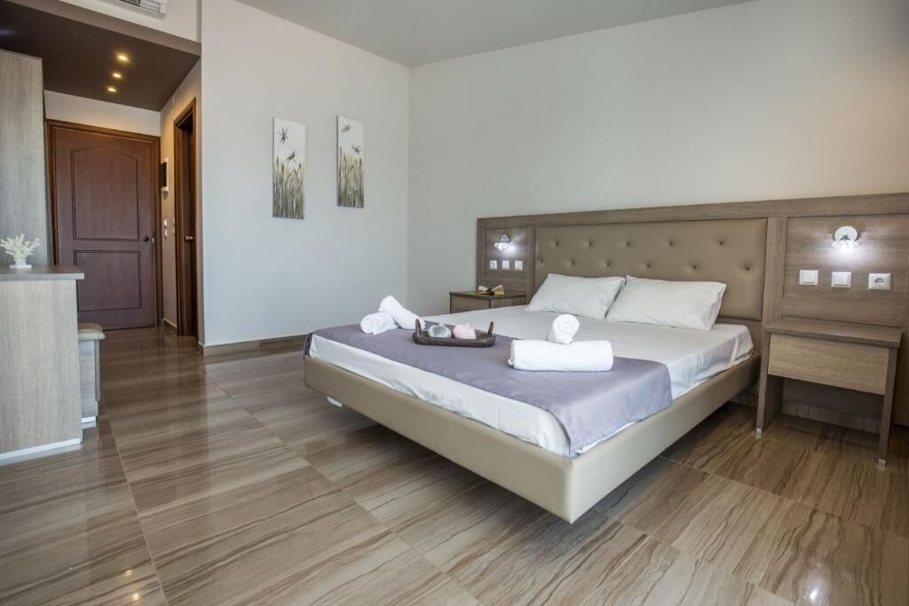 Habitación de hotel con una cama grande, una mesita de noche, cabecero de madera y una obra de arte en la pared.