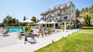 A multi-story hotel with a swimming pool, outdoor seating, and a landscaped garden. - Green Bay Thassos (Thasos)