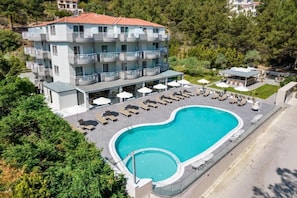 A multi-story hotel with balconies, a swimming pool, and outdoor seating. - Green Bay Thassos (Thasos)