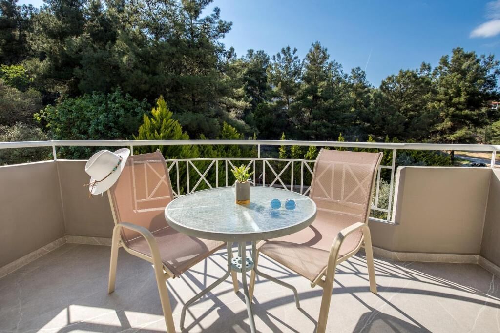 A balcony with two chairs, a small table, and a potted plant.