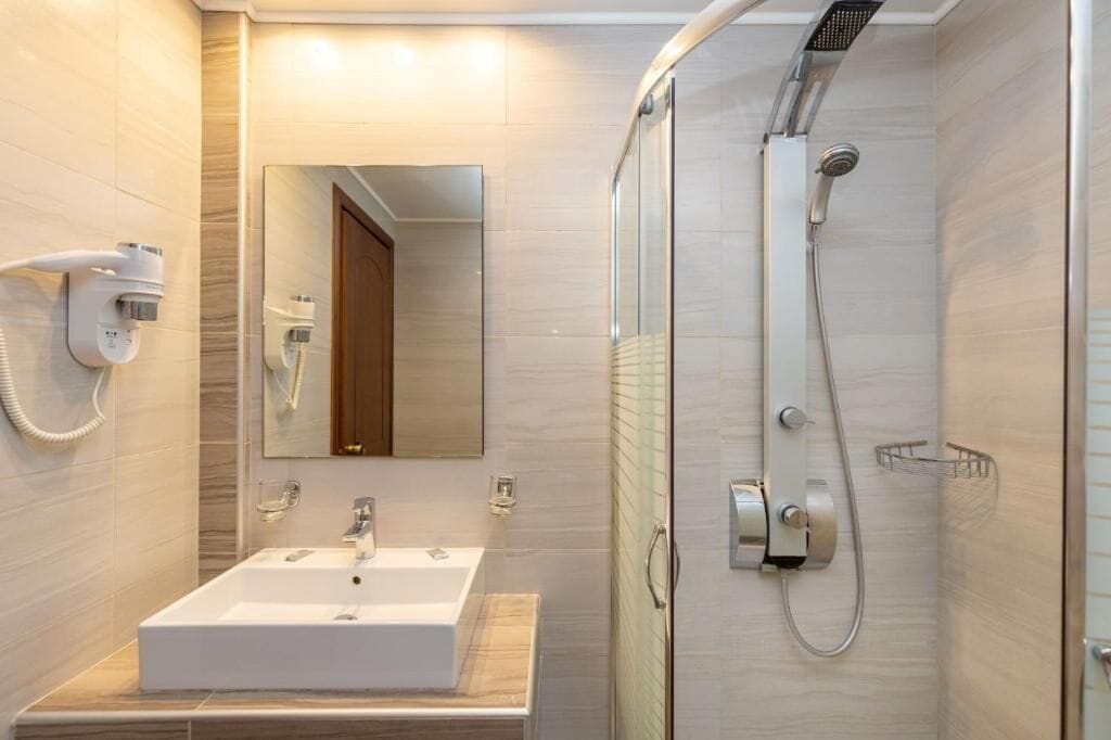 A modern bathroom with a sink, mirror, and shower.