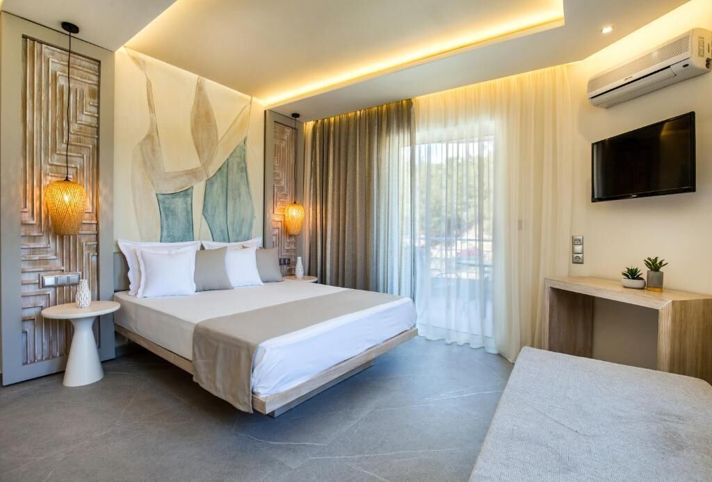 A modern hotel room with a large bed, a bedside table, a TV, and an air conditioning unit.