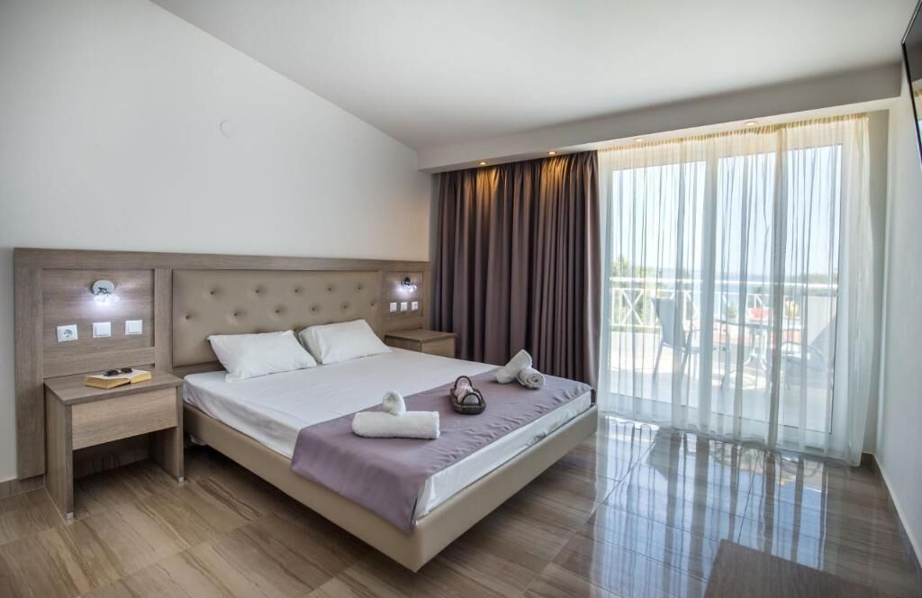 Une chambre d’hôtel avec un grand lit, une table de chevet, une fenêtre avec des rideaux et une vue sur l’extérieur.