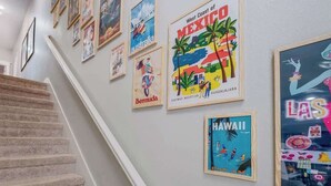Eine Treppe mit Handlauf führt zu einer Empfangsebene, an der verschiedene reisebezogene Plakate an der Wand angebracht sind.
