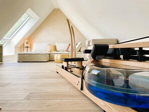Ein modernes Schlafzimmer im Loft-Stil mit schrägverlaufender Decke, einer Holzplattform und einem großen, blauen Aquarium.