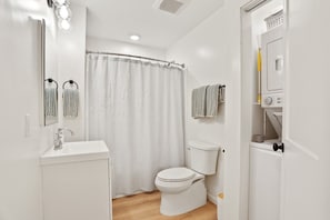 Un baño pequeño con inodoro blanco, lavamanos, espejo y cortina de ducha.
