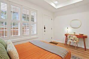 A bedroom with a bed, a desk with a chair, a door, and a skylight. - Cozy Guesthouse in Midtown Savannah (Savannah)
