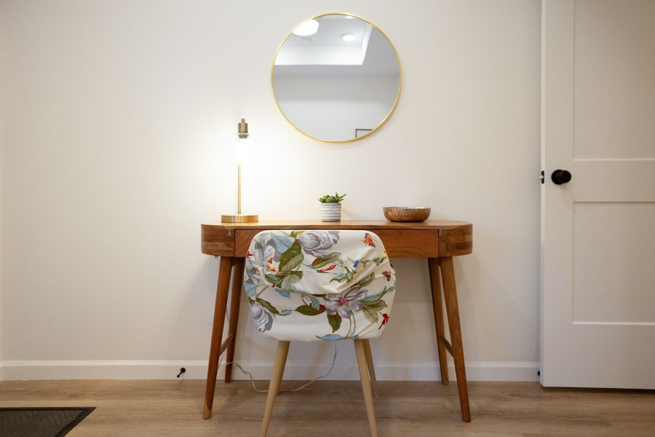 A wooden desk with a round mirror, a small plant, and a bowl.
