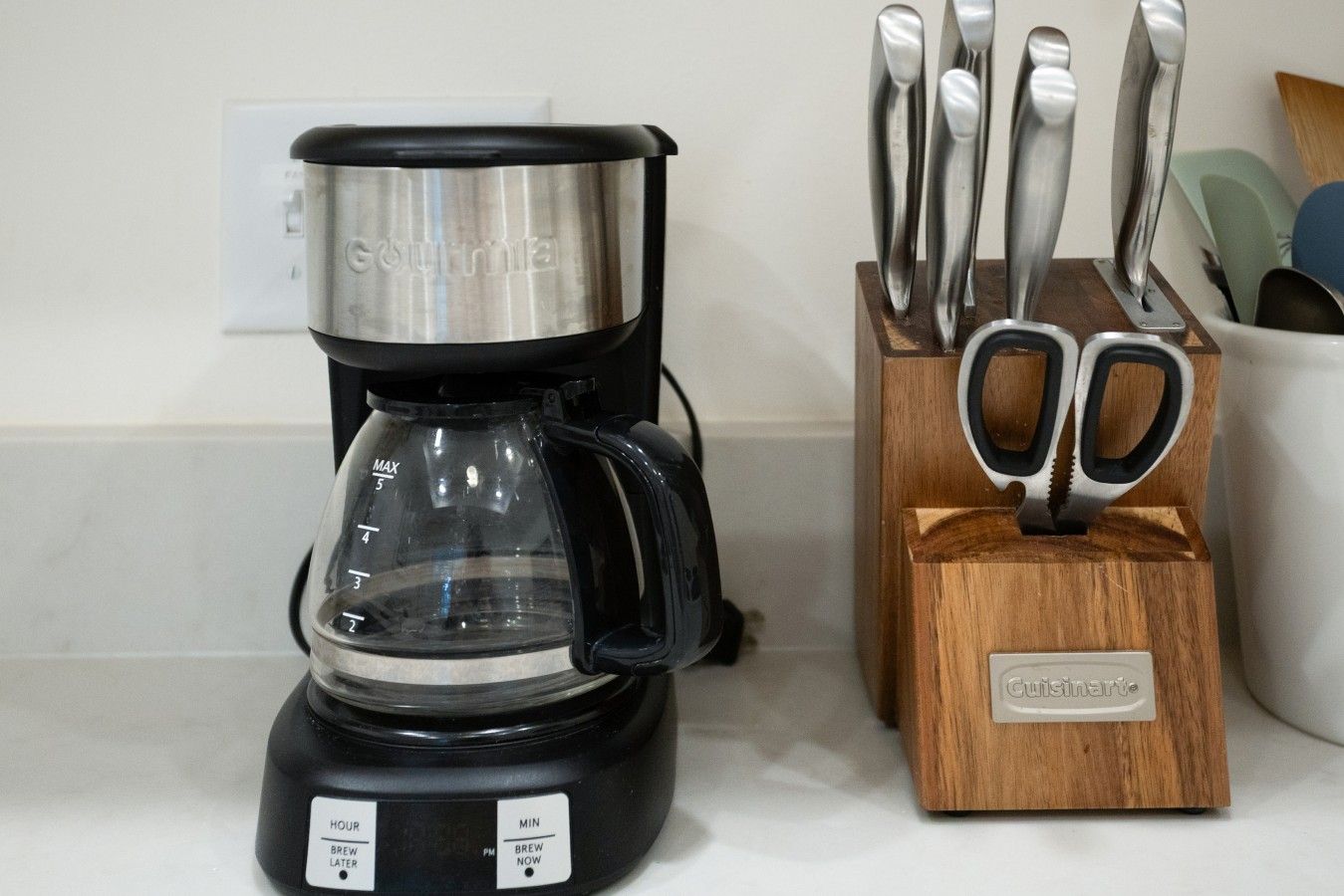 Una cafetera con temporizador y un bloque para cuchillos con utensilios.