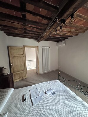 Ein Schlafzimmer mit Bett, Heizkörper, Tür und Fenster.