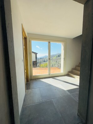 Ein Zimmer mit einer großen Schiebeglasdoor zur Terrasse mit Bergblick.