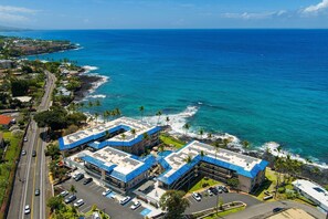 Ein Küstenhotel mit Parkplatz, mehreren Gebäuden mit blauen Dächern und Blick auf den Ozean.