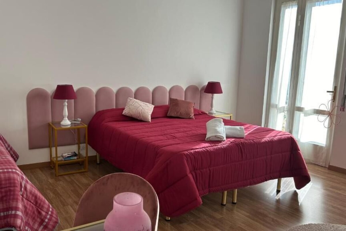 A bedroom with two beds, each with a red bedspread and matching lamps.