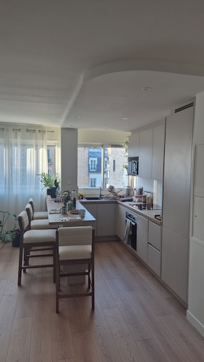 Eine moderne Küche mit Essbereich, Holzboden und Blick auf die Stadt.