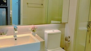 Une salle de bain moderne avec un lavabo blanc, des toilettes et une douche à parois de verre.