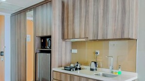 Une cuisine moderne avec des meubles en bois, un réfrigérateur en acier inoxydable, un évier et une bouilloire.