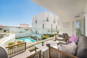 Ein Balkon mit Pool, Korbmöbeln und einem weißen Gebäude im Hintergrund.