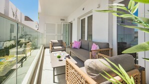 Ein Balkon mit Korbmöbeln, einer Couch und einem Tisch.
