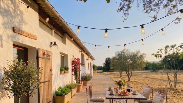 A rustic outdoor dining area with a table and chairs, potted plants, and a sign reading 'Welcome'. - Family B&B in the heart of the horses (Jouques)