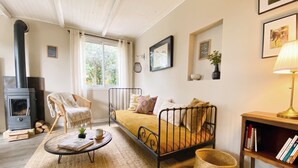 A cozy living room with a sofa, a small table, a bookshelf, a fireplace, and a window with curtains. - Family B&B in the heart of the horses (Jouques)