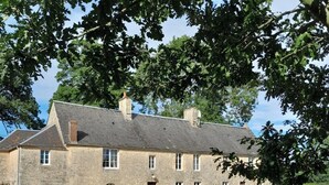 Un bâtiment en pierre doté de nombreuses fenêtres, d’une porte centrale et entouré d’une pelouse.