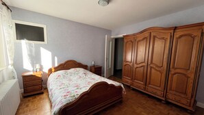Een slaapkamer met een houten bed, een kledingkast, een nachtkastje en een radiator.