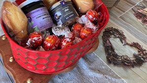 Een tafel met een mand, daarin brood, een pot jam en ingepakte chocolade.