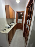 Quarto triplo standard, sacada, vista para a cidade | Cozinha privada | Geladeira, cooktop, talheres/pratos/utensílios de cozinha