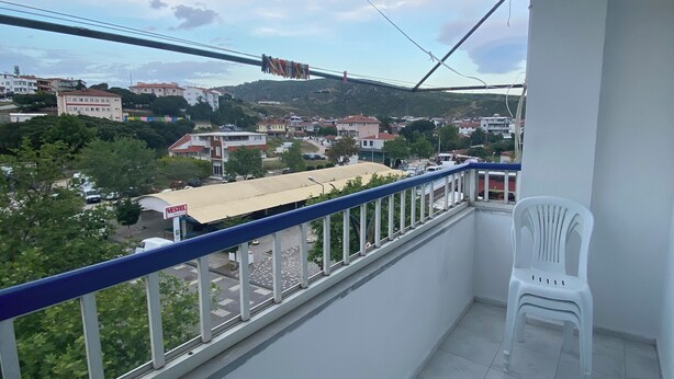 A balcony with a view of a town, a chair, and a sign for a gas station. - Beluna City Apart (Marmara)