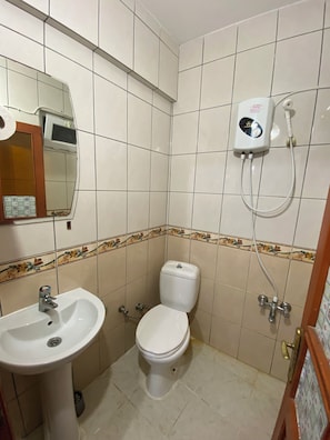 Ein Badezimmer mit Toilette, Waschbecken und einem an der Wand befestigten Händetrockner.