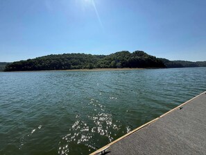 Un lago tranquilo con un muelle de madera que se adentra en el agua, rodeado por una isla boscosa.