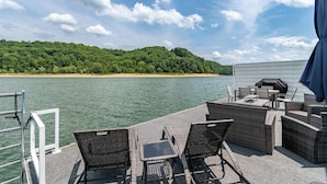 Una terrazza con mobili in vimini, un barbecue e vista su un lago e una foresta.