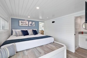 A bedroom with a bed, pillows, a sign on the wall, and a view into the adjacent room. - Lake'n Memories - The Ultimate Oasis Getaway (Russell Springs)