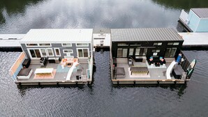 Deux maisons flottantes dotées d’espaces de détente en plein air, d’une piscine et d’un petit bateau amarré à proximité.