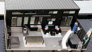 A floating house with a deck, outdoor seating, and a small table.