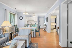 Ein modernes Wohnzimmer mit Essbereich, Küche und einem Flur, der zu den Schlafzimmern führt.