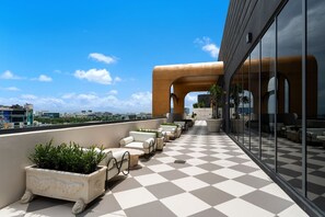 Eine Dachterrasse mit Sitzgelegenheiten im Freien, einem Schachbrettboden und Blick auf die Stadtlandschaft.