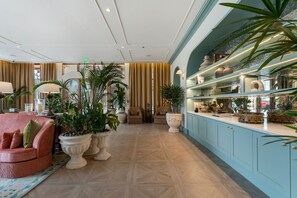 En rummelig lobby med siddeområde, store plantekasser og udstilling af dekorative genstande.