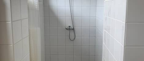 Een douche, handdoeken, zeep, toiletpapier
