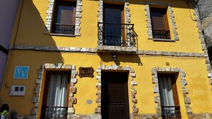 Un edificio de dos plantas con fachada amarilla, detalles de piedra y puerta de madera.