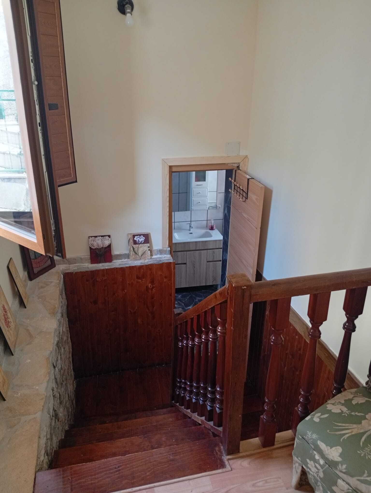 A wooden staircase leading to a bathroom with a sink and mirror.