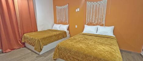 Ein Hotelzimmer mit zwei Betten, orangefarbenen Wänden und einem Vorhang.
