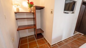 A corner with a wooden shelf, a wall-mounted TV, and a door.