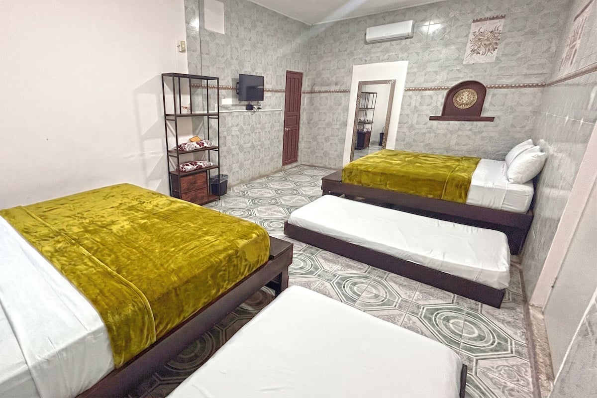 Una habitación con dos camas, televisión, armario y espejo.