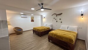 A hotel room with two beds, a ceiling fan, recessed lighting, a wall-mounted air conditioner, and a wicker chair.